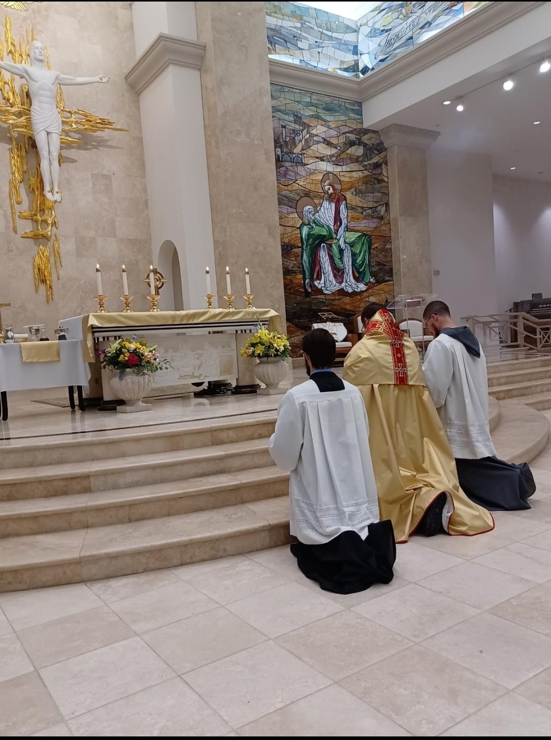 Clergy and altar servers kneeling before the altar